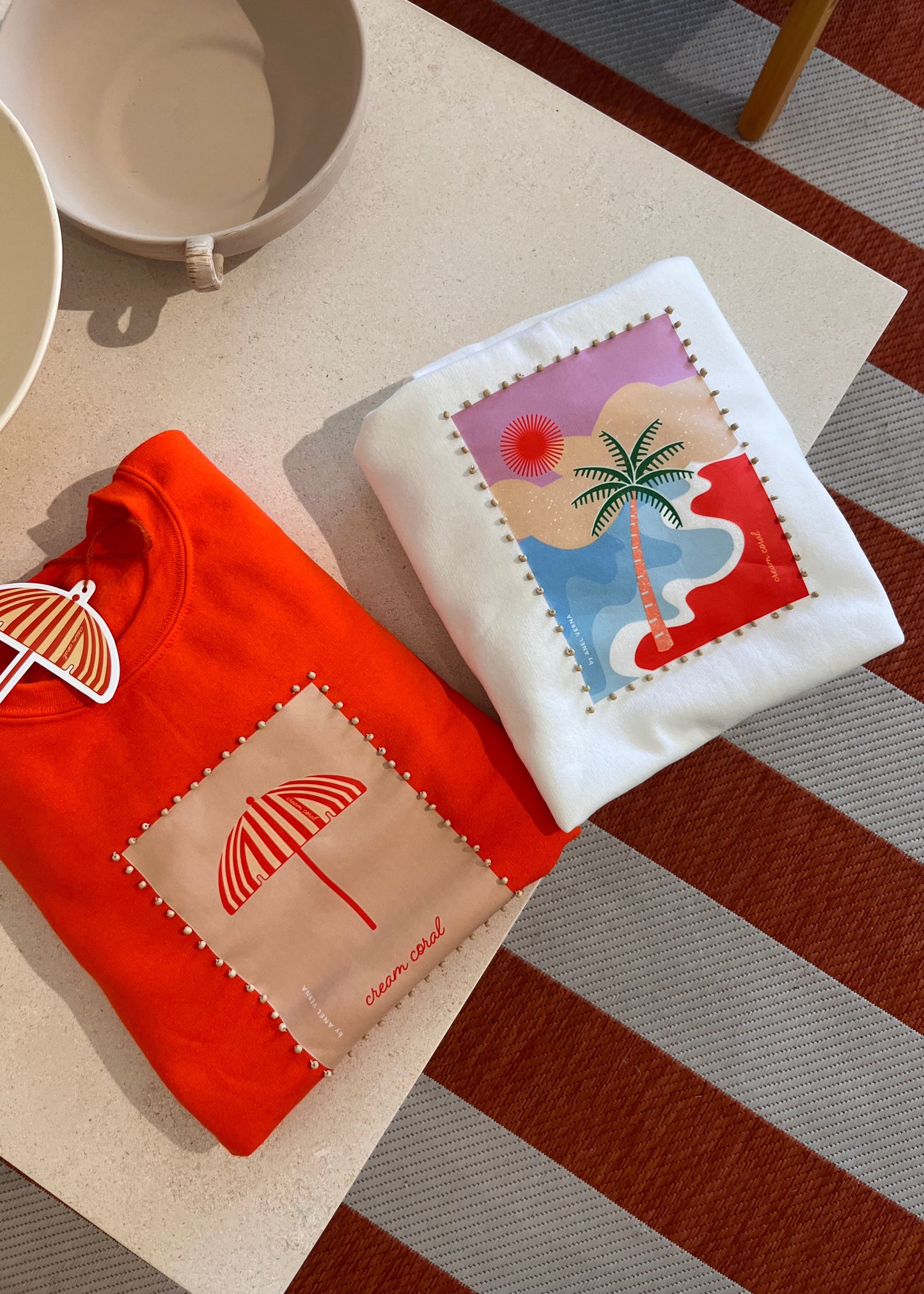 Two sweatshirts folded  with art work and beads