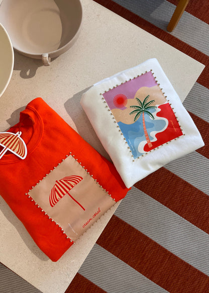 Two sweatshirts folded  with art work and beads