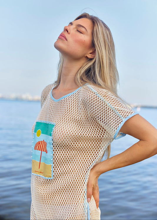 Woman wearing a mesh cover-up with a beach scene design by the water
